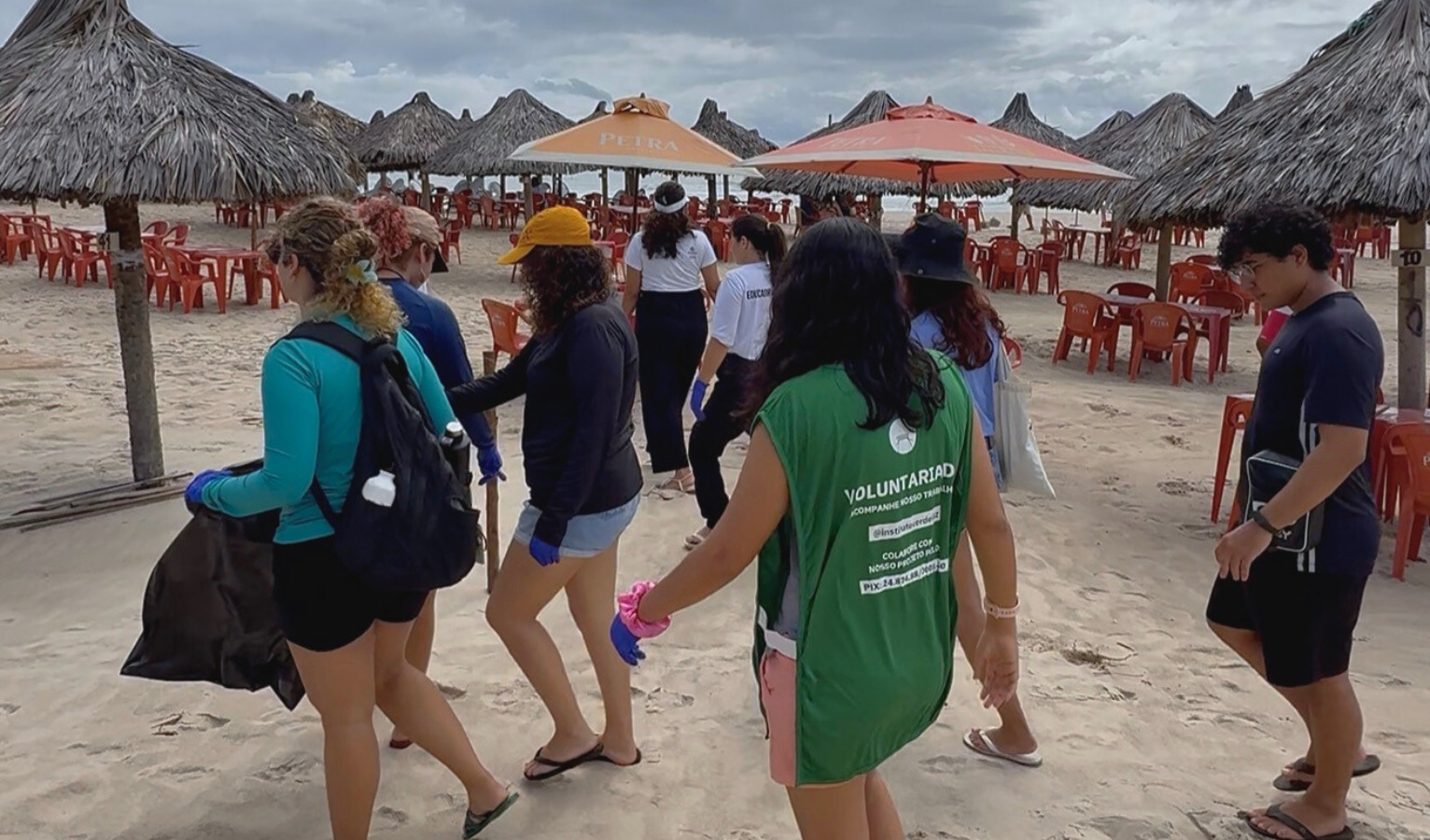 grupo de pessoas voluntárias da seuma caminham numa praia